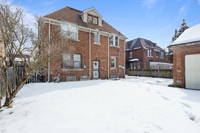 snow covered back of property featuring brick siding