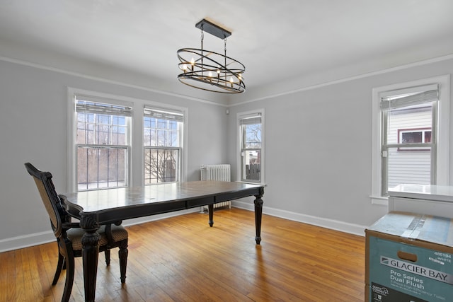 dining area featuring baseboards, a notable chandelier, radiator heating unit, and wood finished floors