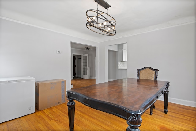 dining room featuring a chandelier, light wood-style flooring, and baseboards