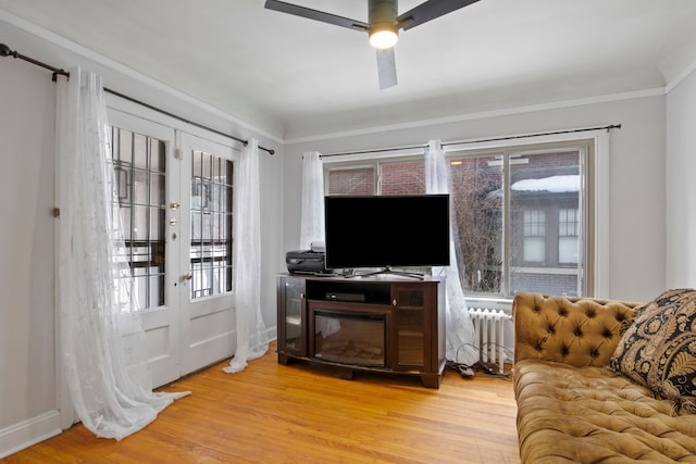 living room featuring a ceiling fan, french doors, light wood finished floors, radiator heating unit, and crown molding