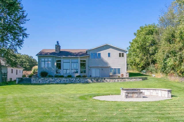 back of property with a patio area, an outdoor fire pit, a chimney, and a yard