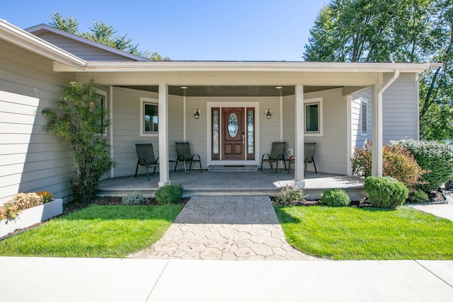 entrance to property featuring a porch and a lawn