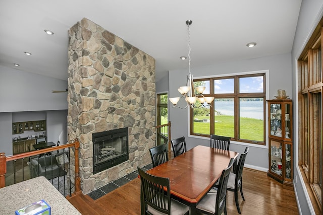 dining space with a stone fireplace, dark wood-style flooring, a water view, and baseboards