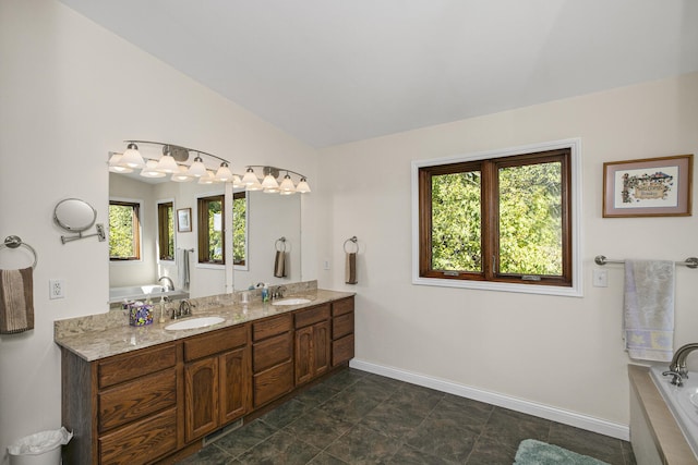 full bathroom featuring lofted ceiling, double vanity, baseboards, and a sink