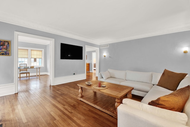 living room featuring baseboards, crown molding, visible vents, and wood finished floors