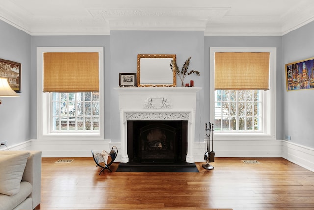 living room featuring a fireplace, wood finished floors, visible vents, and crown molding