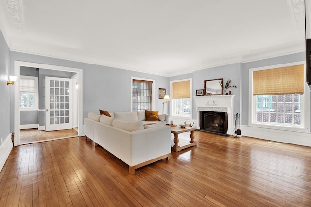 living area with ornamental molding, a fireplace, wood finished floors, and baseboards