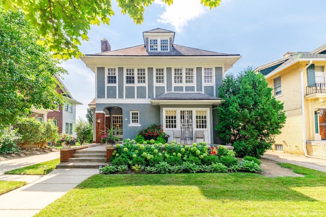 american foursquare style home featuring french doors, a chimney, and a front yard