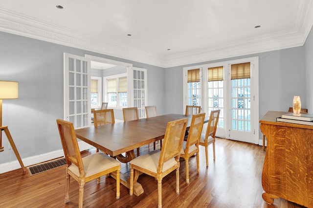 dining room featuring baseboards, visible vents, crown molding, french doors, and light wood-style floors