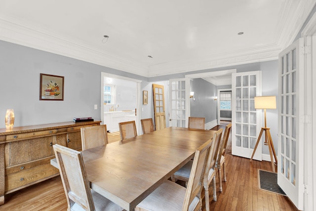 dining space featuring ornamental molding, french doors, visible vents, and light wood-style flooring