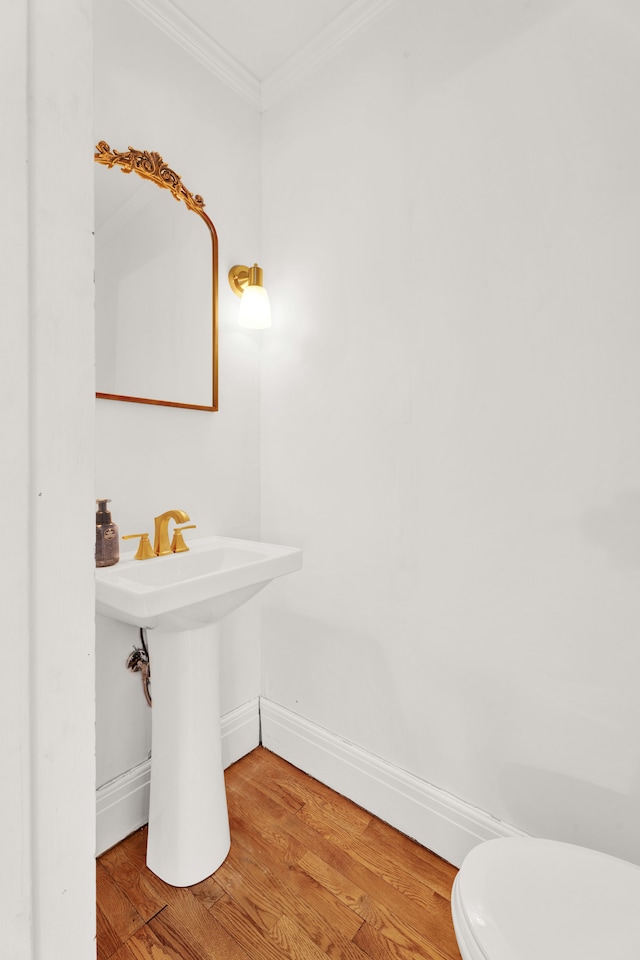 bathroom with ornamental molding, toilet, baseboards, and wood finished floors