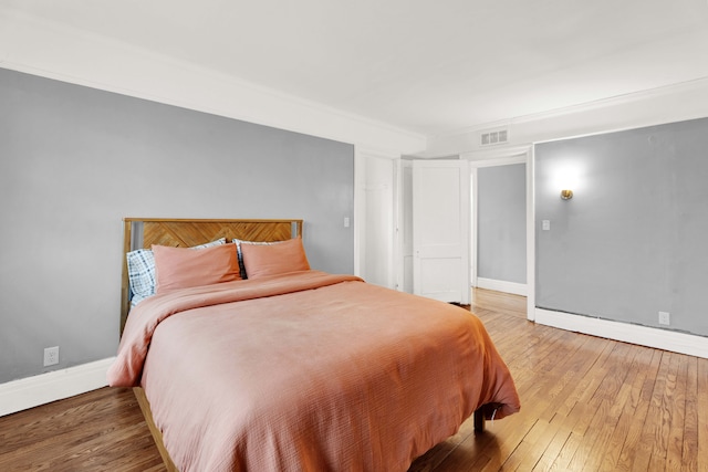 bedroom featuring visible vents, baseboards, and wood finished floors