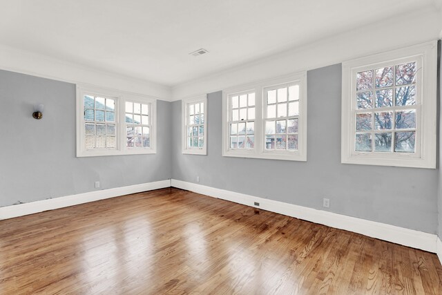 empty room with visible vents, baseboards, and wood finished floors