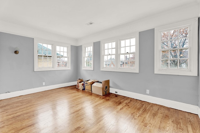 unfurnished room featuring light wood finished floors, visible vents, and baseboards