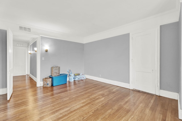 empty room with light wood-type flooring, baseboards, visible vents, and ornamental molding