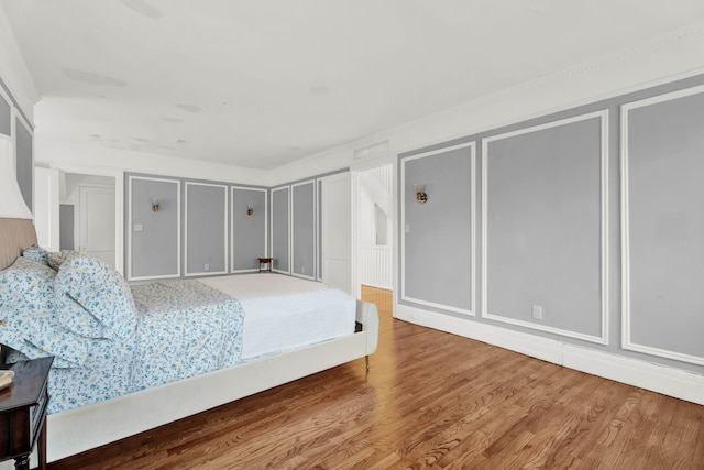 bedroom featuring multiple closets, a decorative wall, and wood finished floors