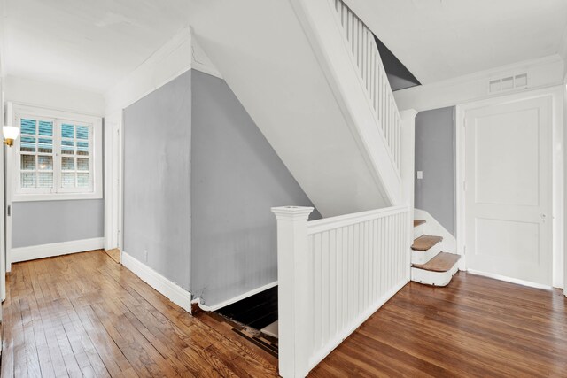 additional living space featuring dark wood-style floors, visible vents, baseboards, and stairs