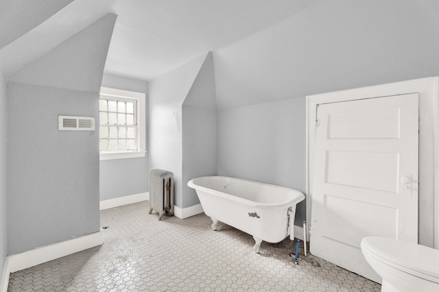 bathroom with toilet, visible vents, baseboards, a freestanding bath, and radiator heating unit