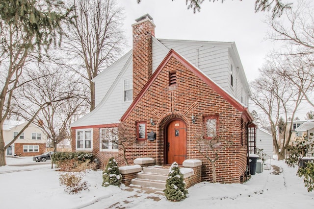 tudor house with a chimney and brick siding