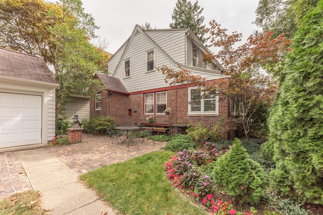 view of front of house with a garage, brick siding, and a patio area