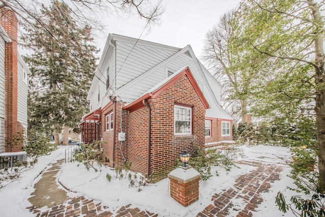 view of snowy exterior with brick siding