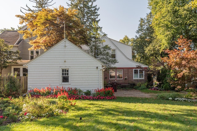 back of property with brick siding, a lawn, and fence