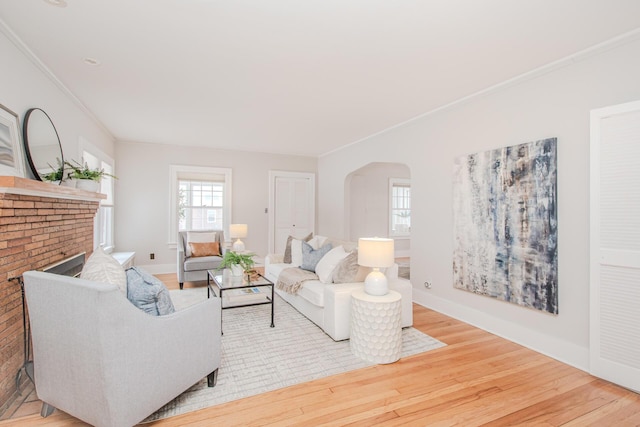 living area with arched walkways, baseboards, wood finished floors, and crown molding