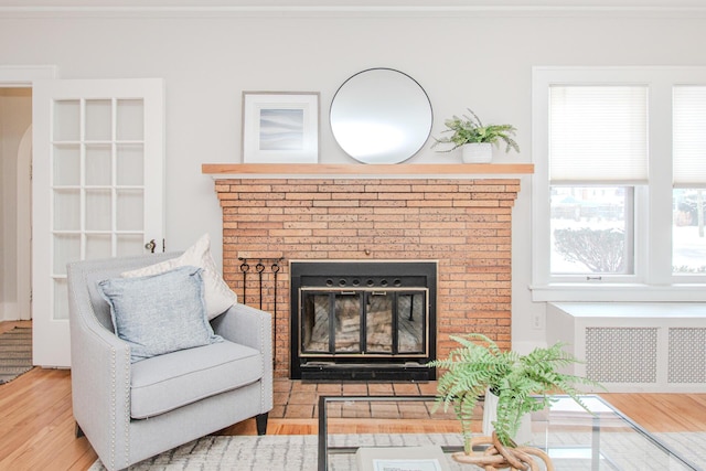 interior space with light wood-type flooring, a brick fireplace, and radiator heating unit