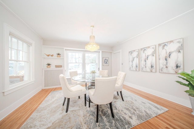 dining space featuring an inviting chandelier, crown molding, baseboards, and wood finished floors