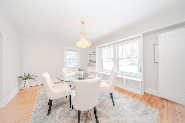 dining space featuring light wood finished floors, baseboards, and crown molding