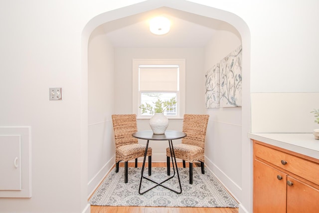 dining room with arched walkways, baseboards, and light wood-style floors