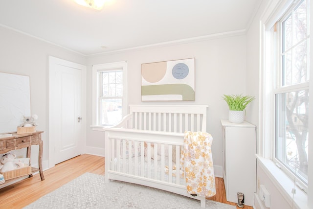 bedroom with baseboards, light wood-style floors, and crown molding