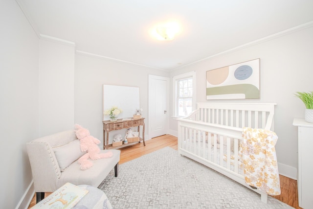 bedroom featuring baseboards, crown molding, and wood finished floors