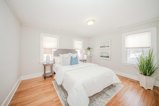 bedroom featuring baseboards, light wood-style flooring, and crown molding