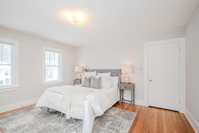 bedroom featuring crown molding, light wood-type flooring, and baseboards