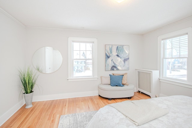 bedroom with multiple windows, radiator heating unit, wood finished floors, and baseboards