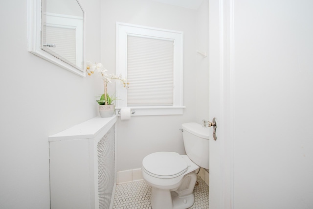 half bath featuring tile patterned flooring, baseboards, and toilet