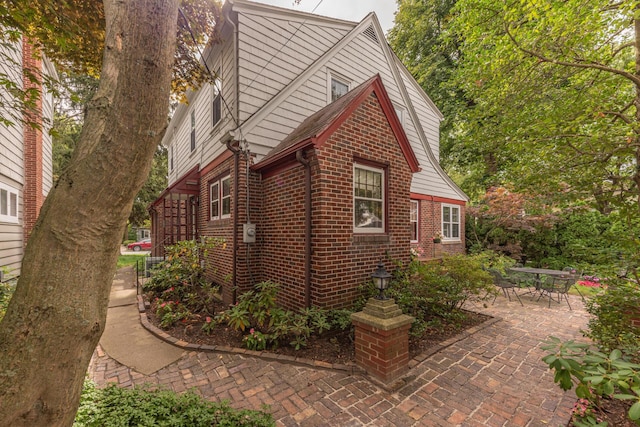 view of property exterior with a patio area and brick siding