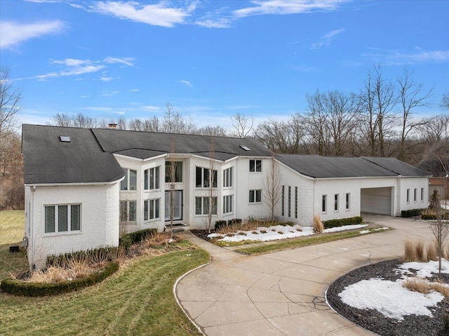 rear view of property featuring concrete driveway, a garage, brick siding, and a chimney