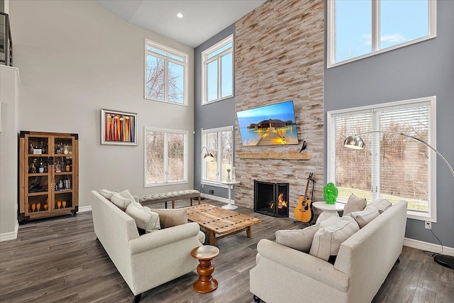 living room featuring a stone fireplace, dark wood-type flooring, recessed lighting, and baseboards