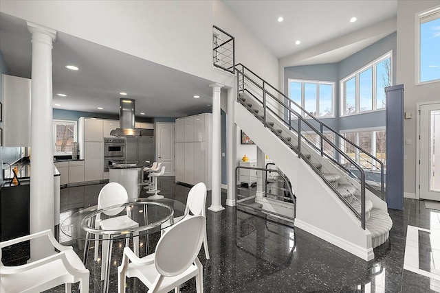 dining space with a high ceiling, granite finish floor, recessed lighting, and ornate columns