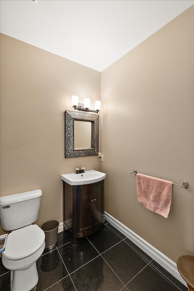 half bath featuring vanity, tile patterned floors, toilet, and baseboards