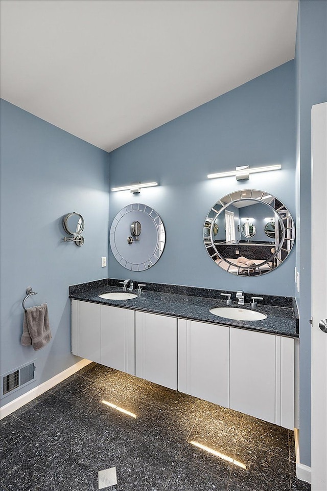 bathroom with double vanity, granite finish floor, visible vents, and a sink