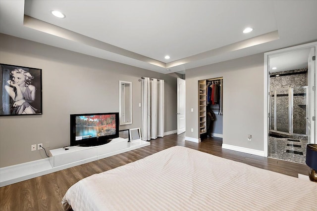 bedroom featuring dark wood finished floors, a raised ceiling, and baseboards