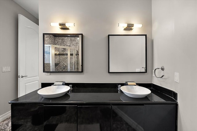 bathroom featuring a shower stall, double vanity, and a sink