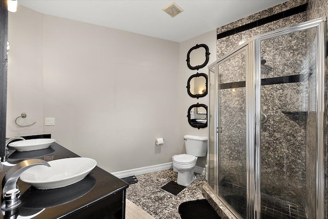 full bath featuring visible vents, baseboards, toilet, double vanity, and a stall shower