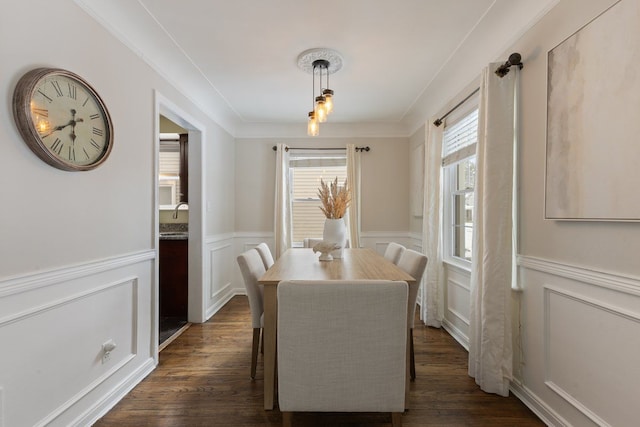 dining room with dark wood-style floors, a wainscoted wall, a decorative wall, and ornamental molding