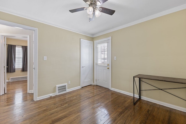 spare room featuring a healthy amount of sunlight, visible vents, crown molding, and wood finished floors