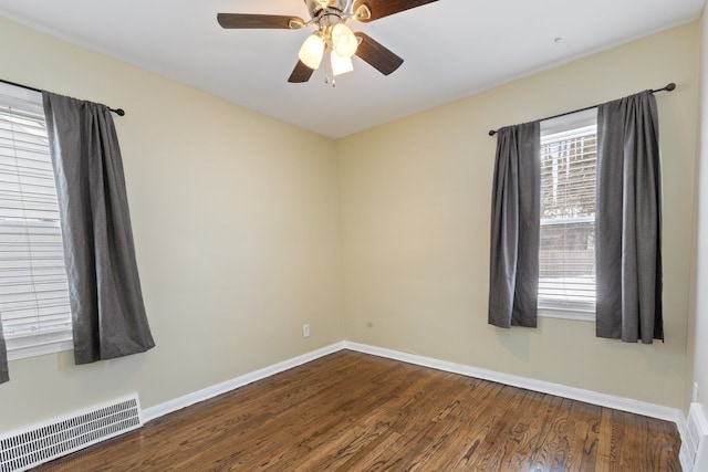 spare room with dark wood-style floors, baseboards, visible vents, and ceiling fan