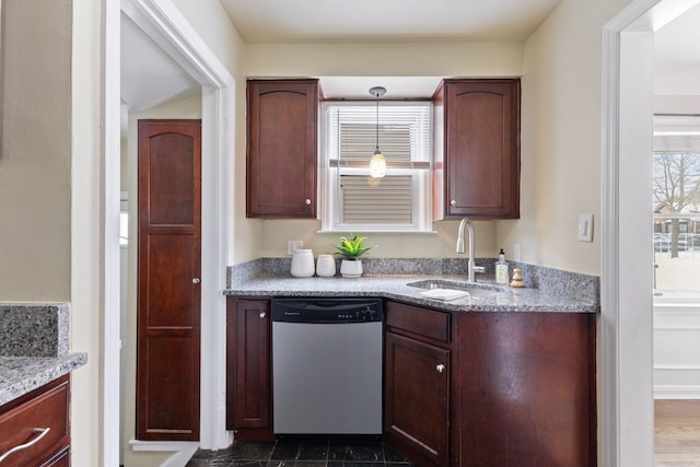 kitchen featuring a sink, light stone counters, stainless steel dishwasher, and decorative light fixtures